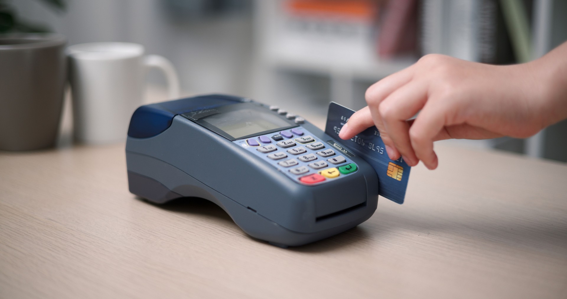 Young woman's hand swiping a credit card with a swipe machine.