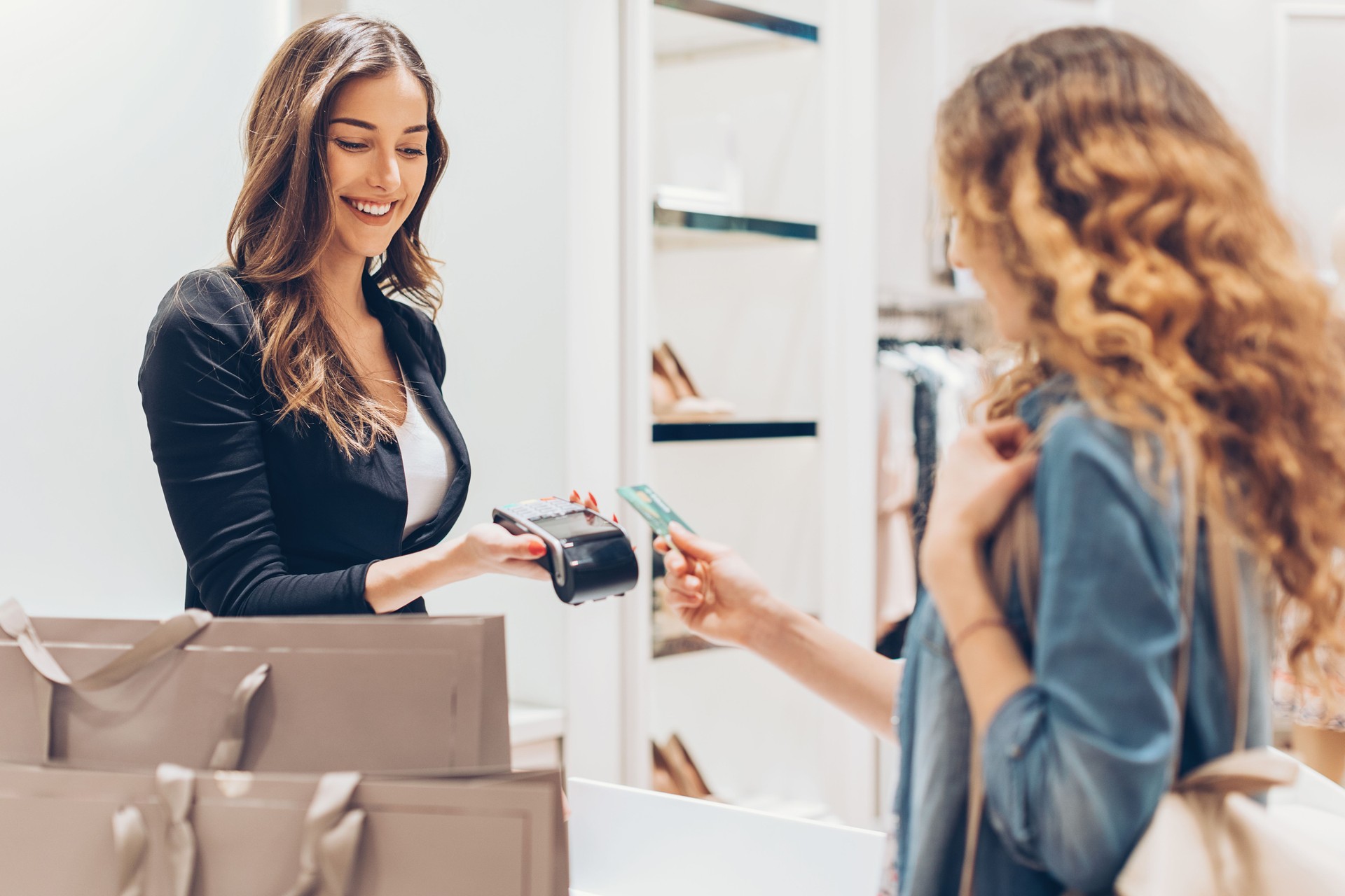 Young woman giving her credit card in the fashion store